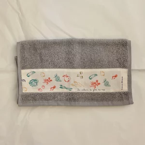 Serviette invités en éponge grise illustrée de fruits et légumes imprimés sur une toile en coton