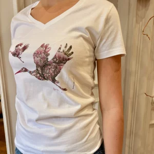 t-shirt col v qui cintre à la taille, il est illustré d'une cigogne remplie d'un magnolia rose